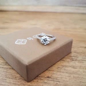 Diamond engagement ring on brown gift box.